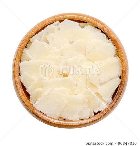 Grana Padano cheese flakes, in a wooden bowl. Italian hard cheese, similar to Parmesan, crumbly-textured, with strong savory flavor and slightly gritty texture, made from unpasteurized cow milk. Photo 96847816