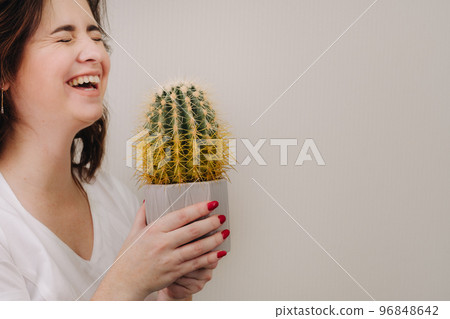 A woman holds a pot with a cactus in her hands. Environmental protection and activism A woman holds a pot with a cactus in her hands. Environmental protection and activism 96848642