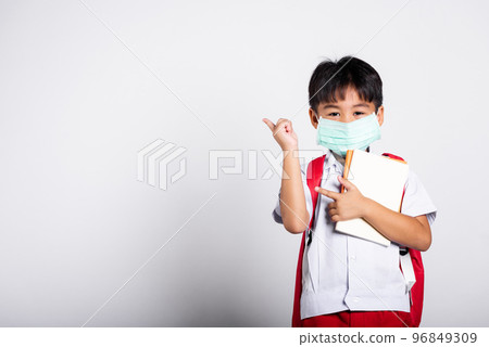 Asian student kid boy wear student thai uniform and protect face mask ready to go to school pointing finger to space in studio shot isolated on white background, preschool, new normal back to school 96849309