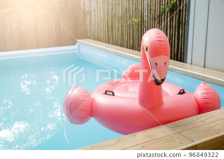 Pink inflatable ring flamingo plastic in the swimming pool blue water, Pool accessory equipment float for party, Trendy summer vacation feeling concept 96849322