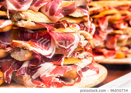traditional Spanish bocadillos with Iberico jamon laid out in a slide on a shop window 96850734
