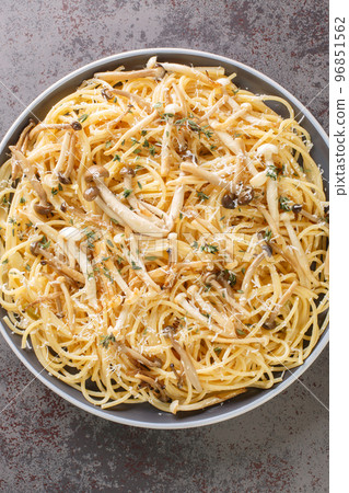 Pasta with brown and white beech mushrooms in a creamy mushroom sauce and thyme closeup on plate. Vertical top view 96851562