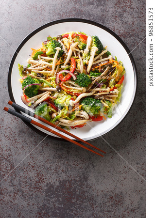 Stir Fried vegetables carrots, peppers, cabbage, broccoli and shimeji beech mushrooms close-up in a plate. Vertical top view 96851573