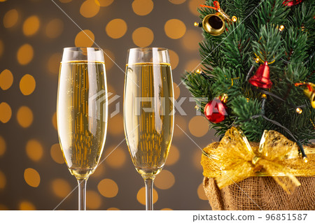 Two wine glasses with bubbly Champagne on blurry sparkling lights background and Christmas tree 96851587