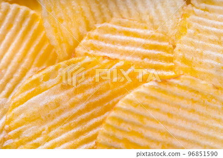 Yellow crispy ridged potato chips close up. Food background Yellow crispy ridged potato chips close up. Food background 96851590