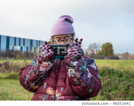 Happy 40 yo woman with the Down Syndrome in winter clothes using a smartphone, Tienen, Belgium Happy 40 yo woman with the Down Syndrome in winter clothes using a smartphone, Tienen, Belgium 96851641