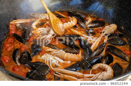 Cooking Italian stew with seafood and tomatoes in a big frying pan, close up Cooking Italian stew with seafood and tomatoes in a big frying pan, close up 96852244