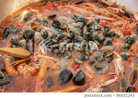 Cooking Italian stew with seafood and tomatoes in a big frying pan,  close up 96852245