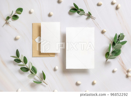 Cards and envelope on a marble table near eucalyptus branches and pebbles top view, Wedding mockup Cards and envelope on a marble table near eucalyptus branches and pebbles top view, Wedding mockup 96852292