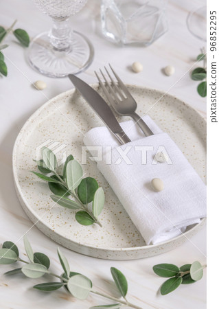 Elegant wedding Table setting decorated with eucalyptus branches and white pebbles close up 96852295