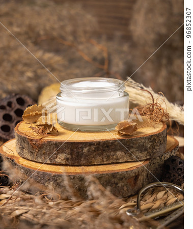 Opened glass cream jar on wood near natural decorations close up. Packaging Mockup 96852307