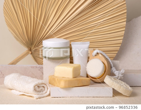 Cosmetic bottles and soap bars on stone against dry beige palm leaf close up, label mockup Cosmetic bottles and soap bars on stone against dry beige palm leaf close up, label mockup 96852336