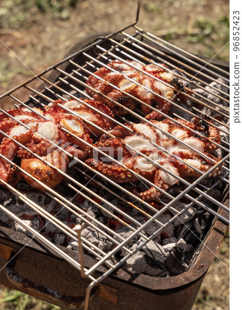 Fresh octopuses on the charcoal grill, Italy. Traditional Mediterranean cuisine. 96852423