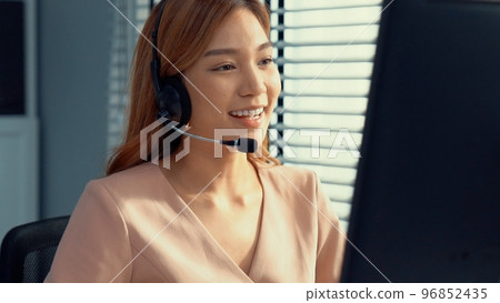 Competent female operator working on computer and while talking with clients. 96852435