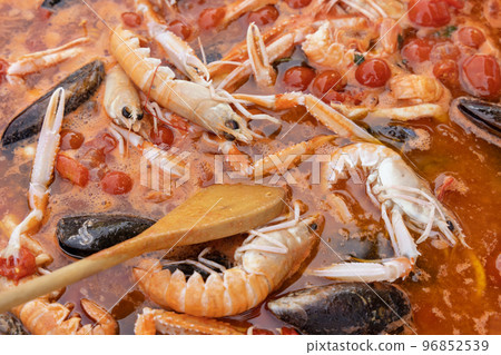 Cooking Italian spaghetti allo scoglio, pasta with seafood and tomatoes close up in a frying pan 96852539