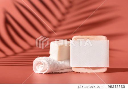 Handmade soap bars with blank label and small towel on pink close up, palm leaf hard shadows Handmade soap bars with blank label and small towel on pink close up, palm leaf hard shadows 96852580