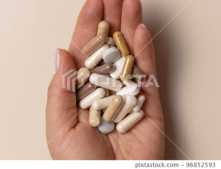 Hand with mix of medical capsules on light beige top view. Taking dietary supplements Hand with mix of medical capsules on light beige top view. Taking dietary supplements 96852593