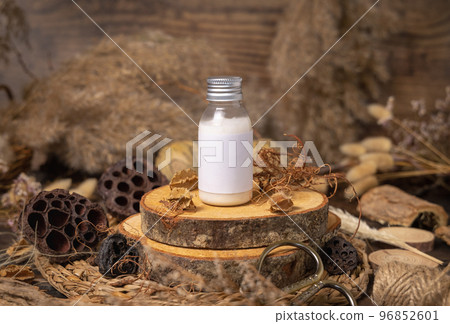 Cosmetic bottle with blank label on wood near natural decorations close up. Packaging Mockup 96852601