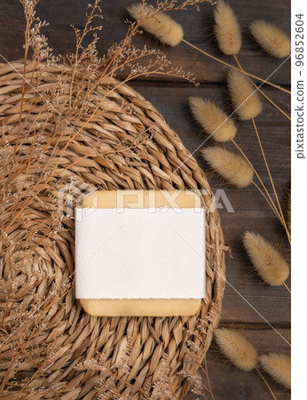Soap bar with blank label on wattled placemat near Hare's Tail grass. Cosmetic Mockup 96852604
