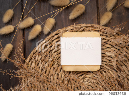 Soap bar with blank label on wattled placemat near Hare's Tail grass. Cosmetic Mockup 96852686
