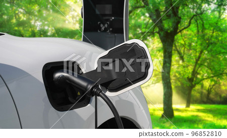 Progressive electric car in the green forest with charging station concept. Progressive electric car in the green forest with charging station concept. 96852810