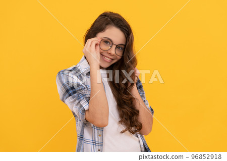 positive teen girl in checkered shirt and glasses on yellow background 96852918