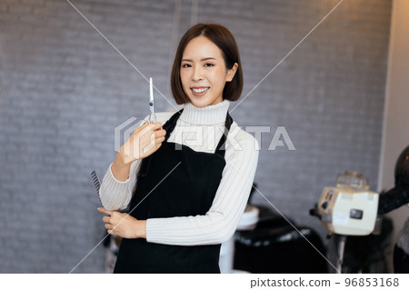 Portrait of a young asian female hairdresser holding qualified haircut tools. Portrait of a young asian female hairdresser holding qualified haircut tools. 96853168