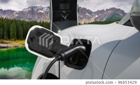 Progressive travel concept by EV car in remote mountain with charging station. Progressive travel concept by EV car in remote mountain with charging station. 96853429