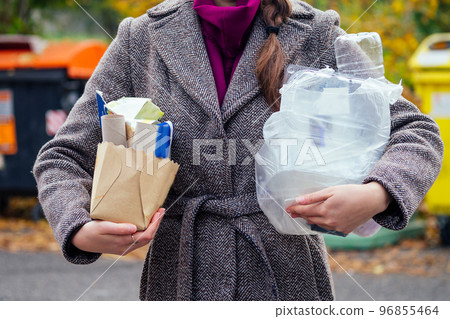 Aware woman separating paper from other waste, putting it into green container to save natural resources in Prague Chezh Aware woman separating paper from other waste, putting it into green container to save natural resources in Prague Chezh 96855464