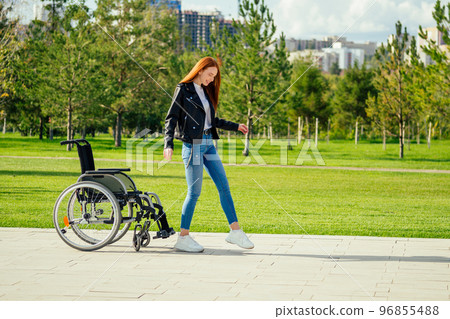 redhaired ginger woman making first steps after long recovery.she walking without her wheelchair in spring park 96855488