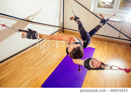 Sporty young caucasian woman doing stretching exercises of full body muscles workout on stretch aerobic aero strap in gym,yogi mat 96855855