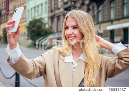 Beautiful rich casual blonde stylish fashion business woman with a phone in her hand make selfie in European buildings and street 96855987
