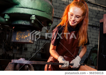 redhead ginger woman blacksmith portrait in workshop 96856018