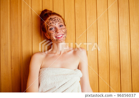 redhaired ginger young woman peeling face with brown sugar in traditional russian banya.steaming and self-care in finnish sauna 96856037