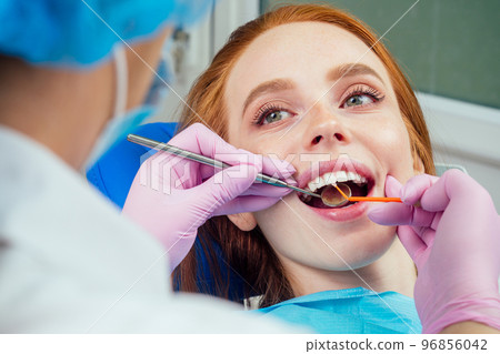 Portrait of an attractive smiling redhaired ginger customer girl in a dental chair in dental cabinet.She is not fear Portrait of an attractive smiling redhaired ginger customer girl in a dental chair in dental cabinet.She is not fear 96856042