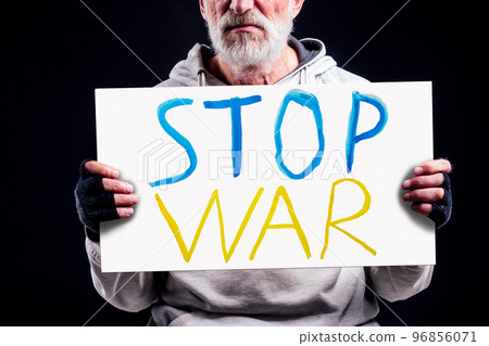 poor caucasian old men with cardboard text stop war in studio black background. Russian versus Ukraine trade third world war disputes and anctions policy concept poor caucasian old men with cardboard text stop war in studio black background. Russian versus Ukraine trade third world war disputes and anctions policy concept 96856071