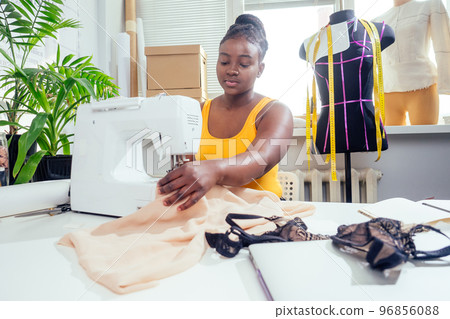 beautiful african american tailor woman sewing laces sexy lingerie in showroom 96856088
