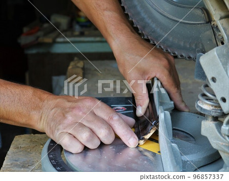 working with a miter saw in a carpenter's workshop, close-up, cutting a wooden fillet on a circular machine, trying on a trimming bar on a miter cut on a work surface working with a miter saw in a carpenter's workshop, close-up, cutting a wooden fillet on a circular machine, trying on a trimming bar on a miter cut on a work surface 96857337