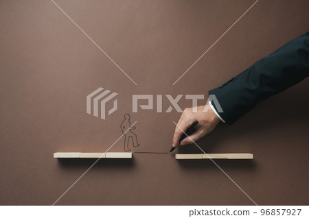 Silhouette of a man walking over a bridge between two sets of wooden pegs Silhouette of a man walking over a bridge between two sets of wooden pegs 96857927