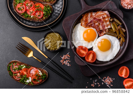 Tasty breakfast consists of eggs, bacon, beans, tomatoes, with spices and herbs 96858842