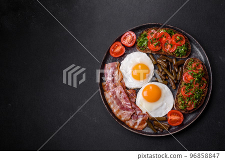Tasty breakfast consists of eggs, bacon, beans, tomatoes, with spices and herbs 96858847