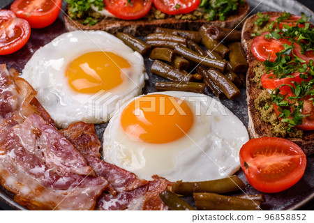 Tasty breakfast consists of eggs, bacon, beans, tomatoes, with spices and herbs 96858852