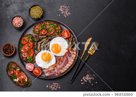Tasty breakfast consists of eggs, bacon, beans, tomatoes, with spices and herbs Tasty breakfast consists of eggs, bacon, beans, tomatoes, with spices and herbs 96858860