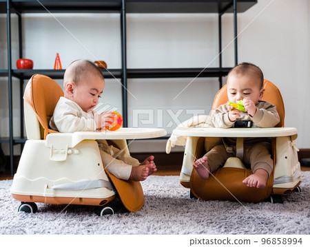 Asian twin babies sitting on safety chair, the chair can use for car seats, Two little baby waiting to eat at home 96858994