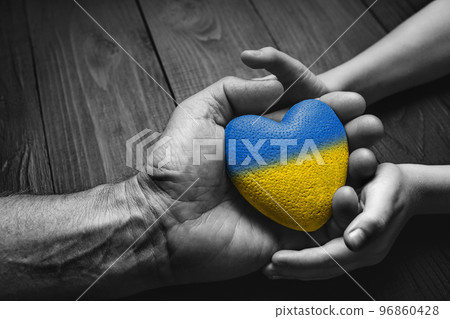 blue and yellow heart in hands 96860428