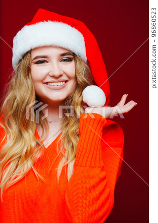 a beautiful woman in a Santa Claus hat on a red background. a beautiful woman in a Santa Claus hat on a red background. 96860523