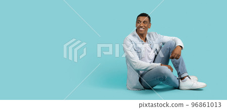 Smiling handsome young african american male in casual sit on floor, look back at free space, enjoy spare time 96861013