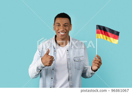 Smiling young african american man student in casual showing thumb up and Deutschland flag Smiling young african american man student in casual showing thumb up and Deutschland flag 96861067