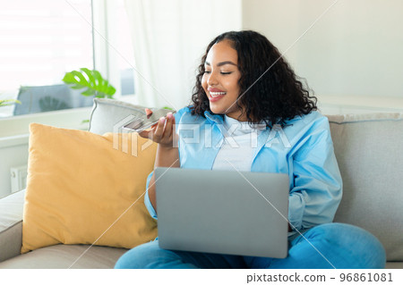 Portrait of young black chubby woman using laptop and talking on speakerphone, dictating voice message 96861081