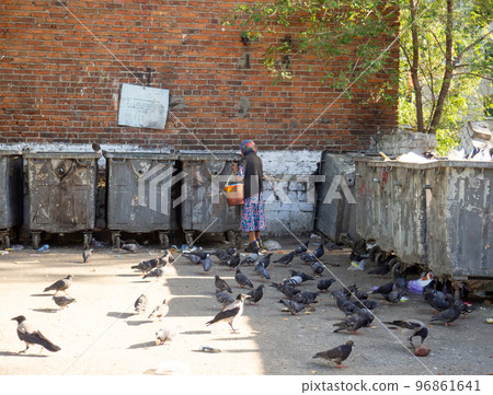 A beggar woman by the trash cans. Old lady with bucket A beggar woman by the trash cans. Old lady with bucket 96861641